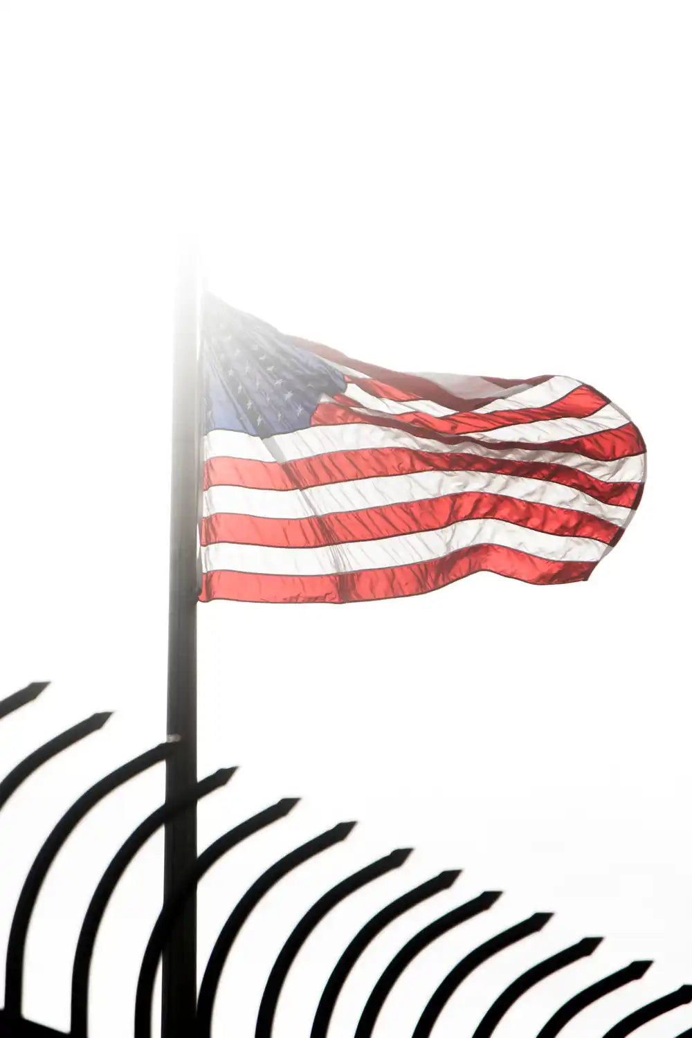 An American flag backlit by the sun, waving in the wind.