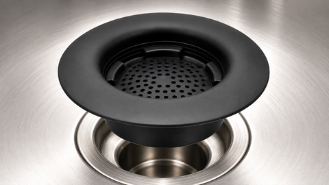 Black basket-style sink strainer positioned above a stainless-steel kitchen drain.