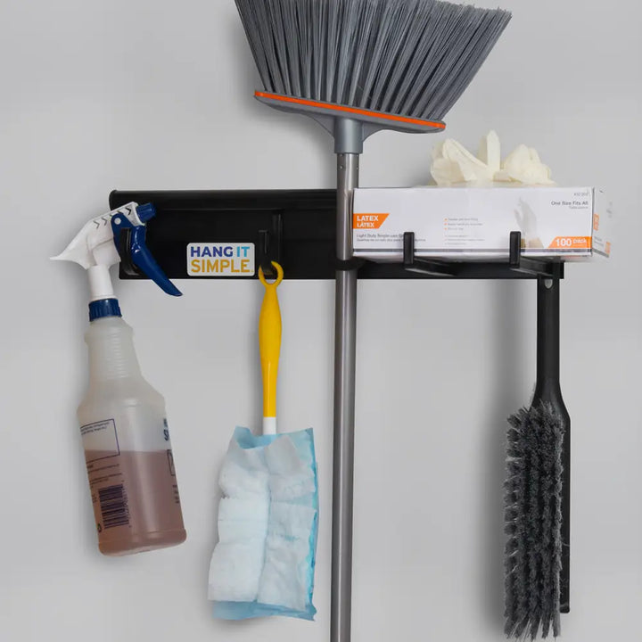 Black broom on wall-mounted hooks with spray bottle storage