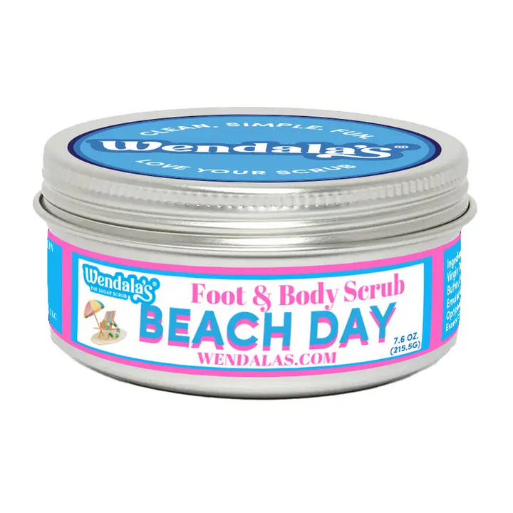 A silver metal jar of wendalas beach day foot and body scrub with vibrant pink and blue label featuring unrefined shea butter and organic coconut butter