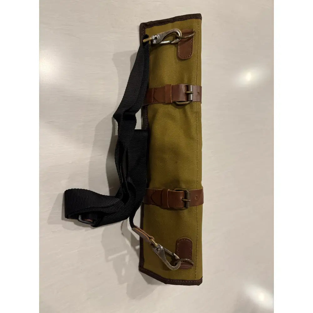 Olive green canvas knife roll with brown leather straps and metal buckles featuring dedicated knife pockets