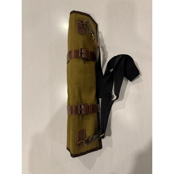 Olive green waxed canvas knife roll bag with brown leather straps and black adjustable shoulder strap for chefs