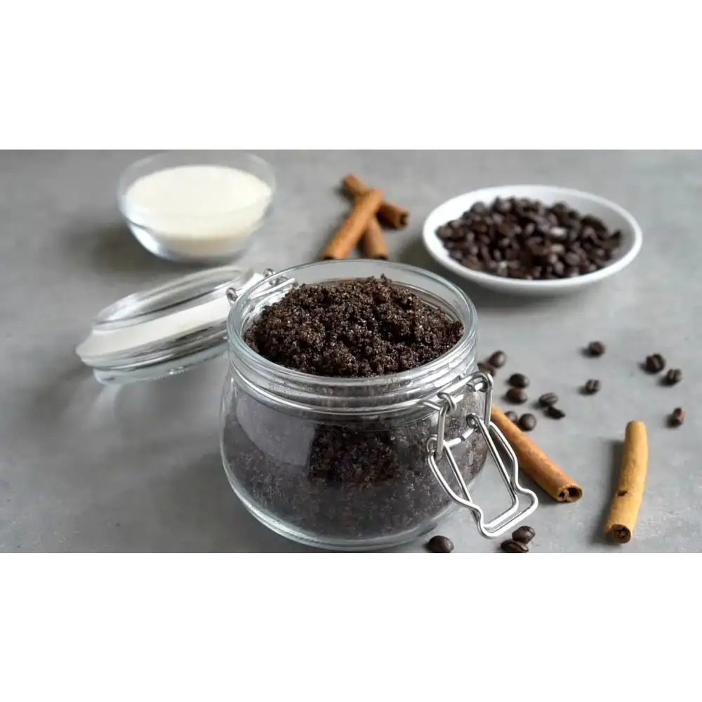 A clear glass jar with silver clasp lid filled with dark brown coffee scrub with brown sugar and organic coconut