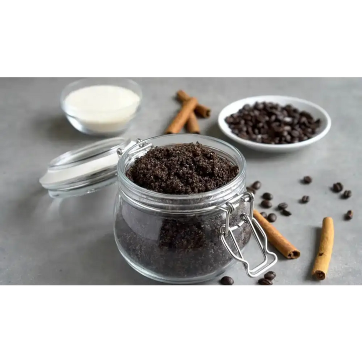 A clear glass jar with silver clasp lid filled with dark brown coffee scrub with brown sugar and organic coconut