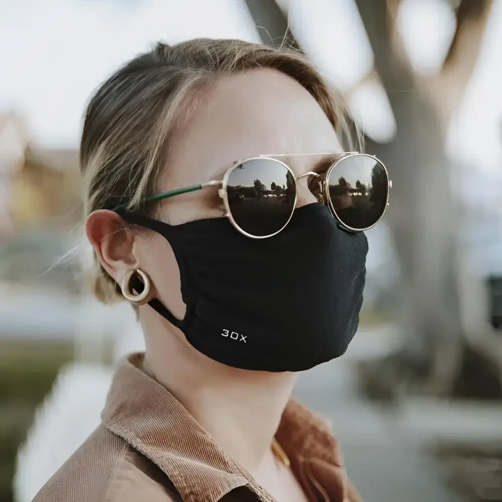 A person wearing a black breathable smart temp face mask with ear loops for all-day protective face mask comfort