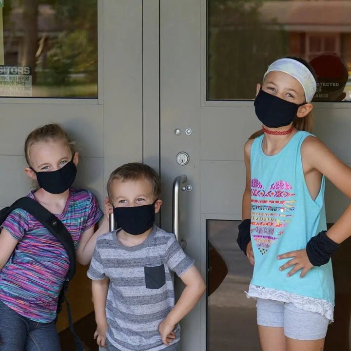 Three young children wearing black breathable smart temp protective face masks with 30xmask ear loop for all-day comfort