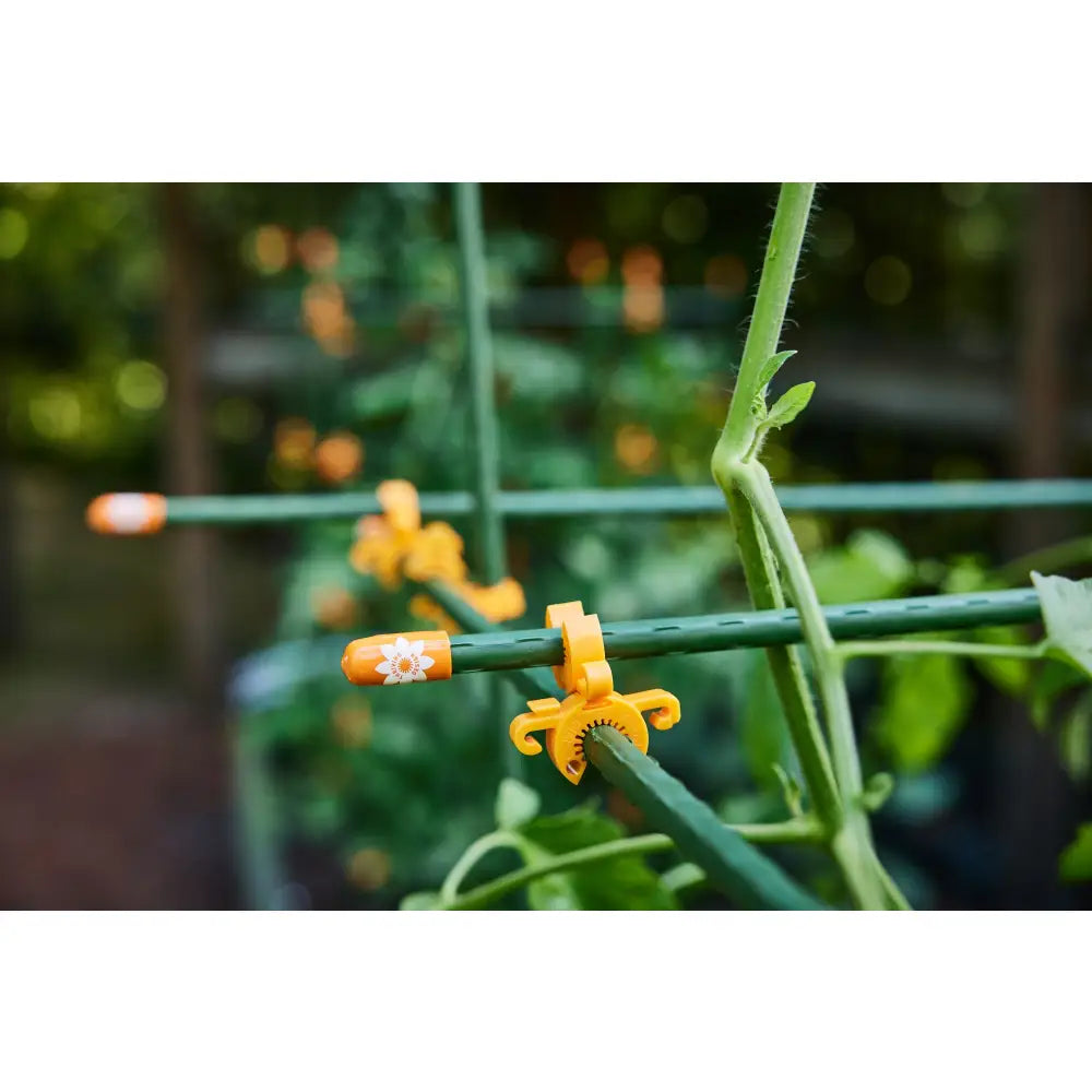 Bright orange plastic tomato plant clips with white floral designs for garden stake and temporary landscape fencing use