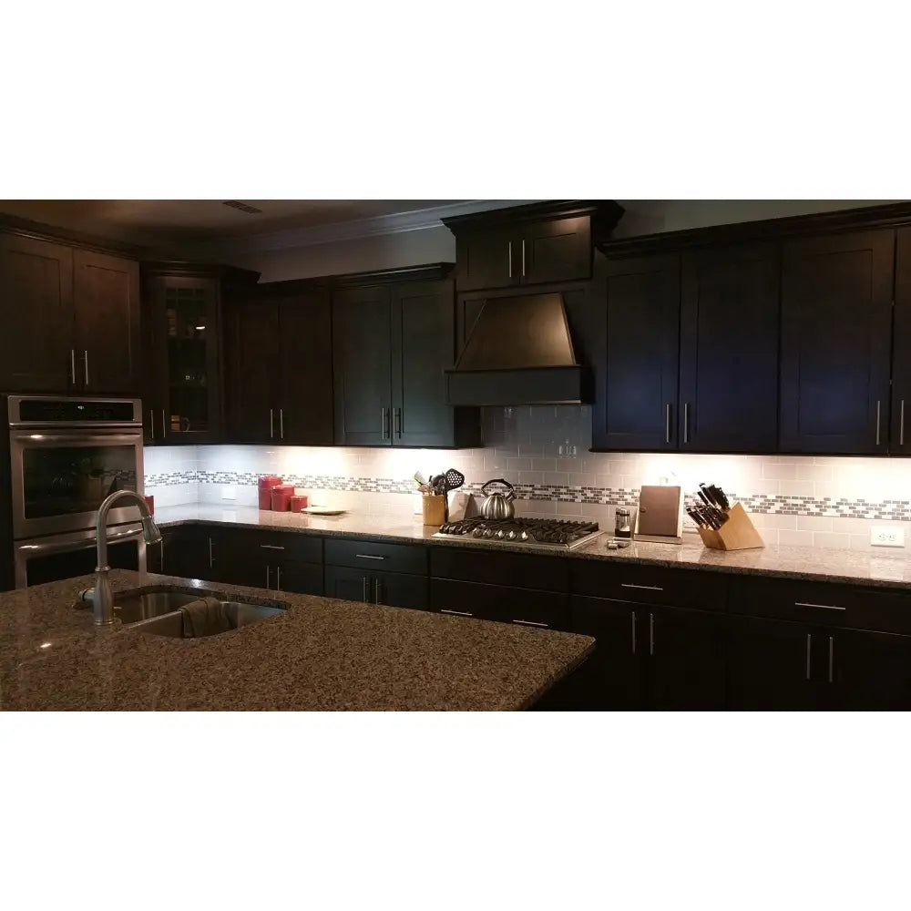 Dark wood kitchen cabinets with silver handles and granite countertop featuring FLI Products 12 inch 400 lumen cabinet led task light