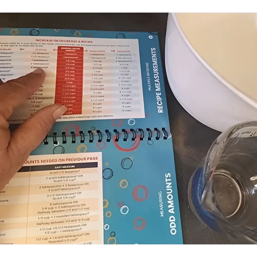 Blue spiral-bound handy kitchen reference cooking cheat sheet booklet with colorful patterns and measurement charts
