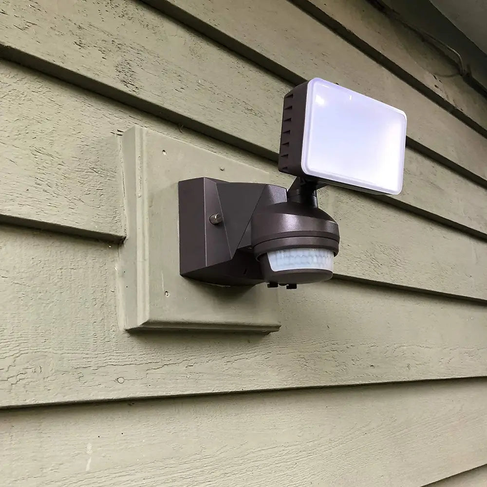 Brown IQ America LED motion security light with rectangular white LED panel and circular sensor base for outdoor security