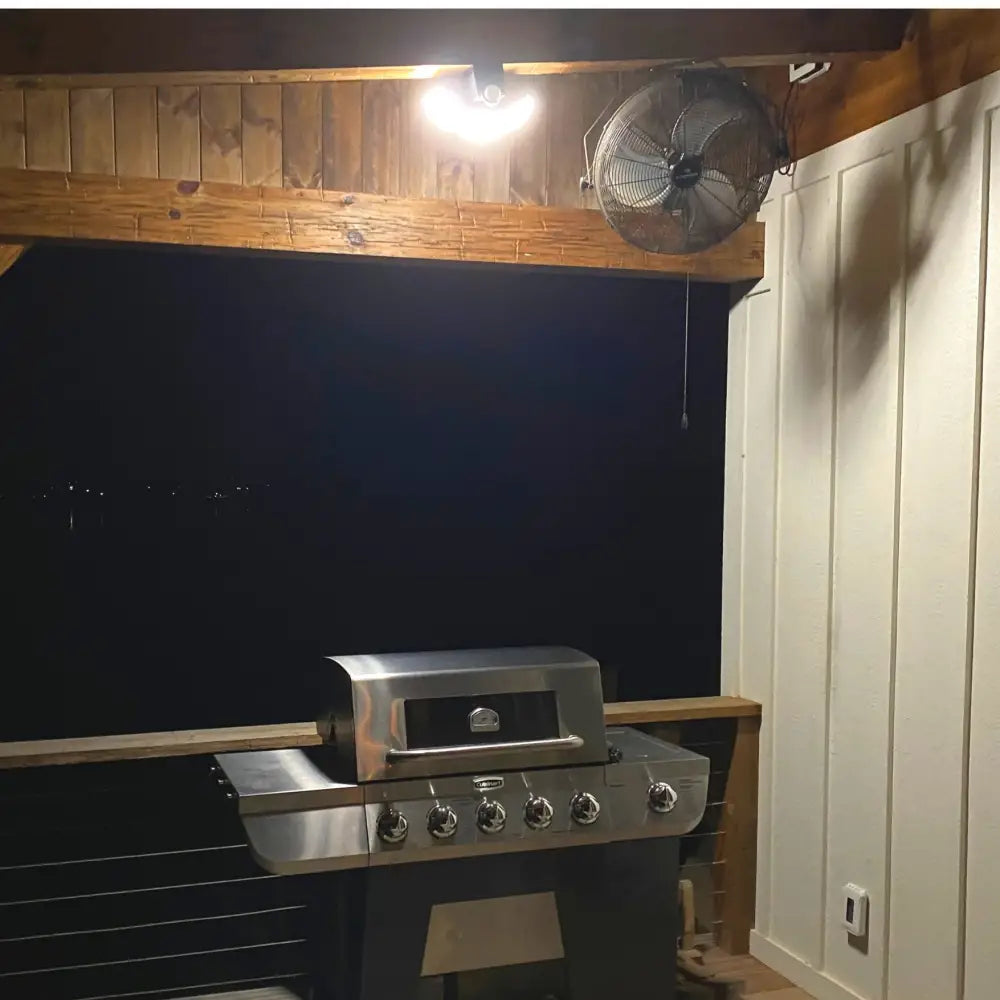 Stainless steel gas grill with six control knobs shown alongside iq america battery powered security light with motion sensor flood light features