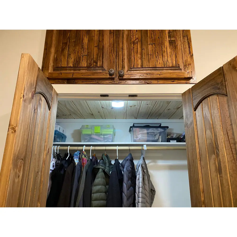 Wooden cabinet with arched doors and rustic finish shown under iq america led motion security eave mount light