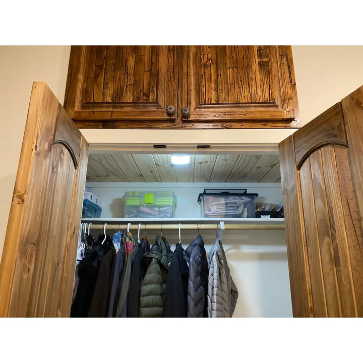 Wooden cabinet with arched doors and rustic finish shown under iq america led motion security eave mount light