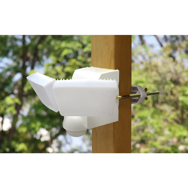 White plastic battery powered motion security light with motion sensor floodlight mounted on wooden post