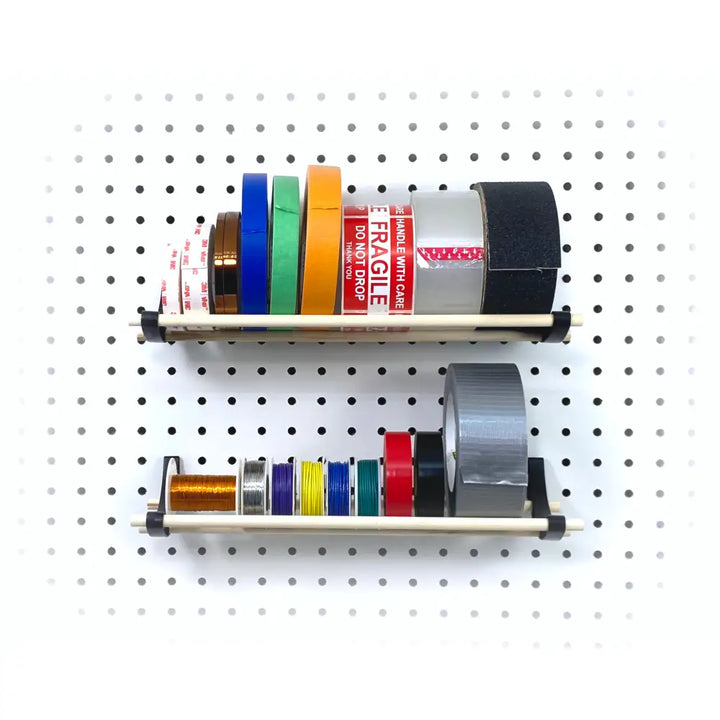 Two beige metal tape and wire organizers mounted on a pegboard for craft rooms by Peggy pegboard organizer