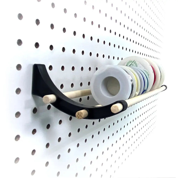 Black curved wall-mounted peggy pegboard organizer with wooden pegs holding colorful spools for craft rooms ribbon organizer