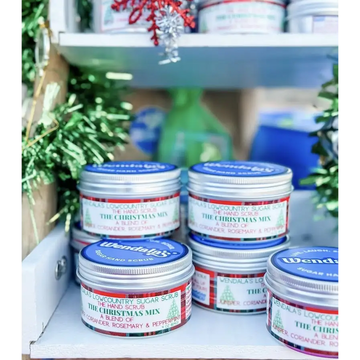 Silver tin containers with blue lids and festive red green plaid labels featuring wendals lowcountry sugar scrub christmas mix hand scrub