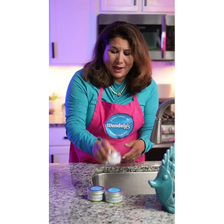 Pink apron with blue wendal’s logo promoting the hand scrub-beach day made with pure cane sugar and organic coconut butter