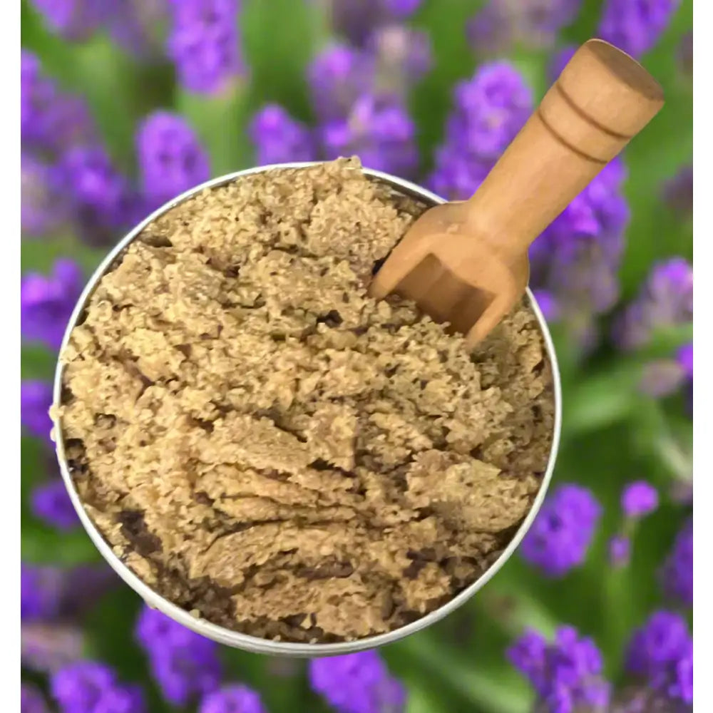 A rustic wooden spoon in a silver bowl with coarse earthy brown granules of wendalas coffee lavender body scrub organic ground coffee