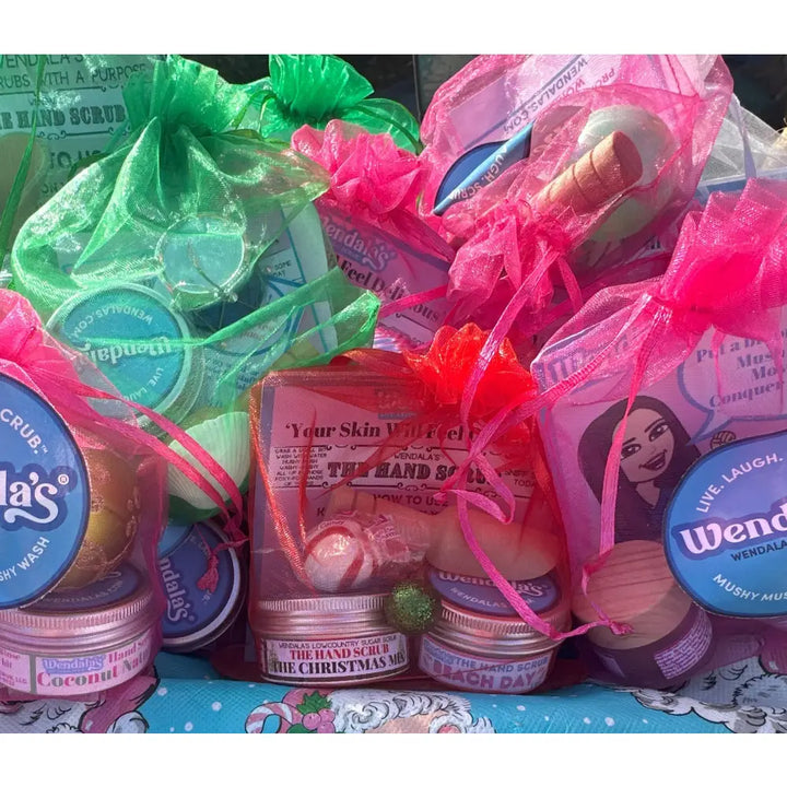 Pink mesh drawstring bags filled with colorful organic coconut wendalas hand scrub bundle lotions and scrubs
