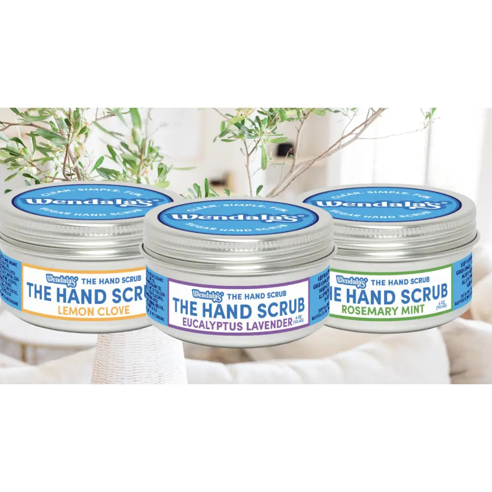 Three silver-topped jars of wendala’s hand scrub bundle with lemon clove eucalyptus lavender and rosemary mint scents organic coconut
