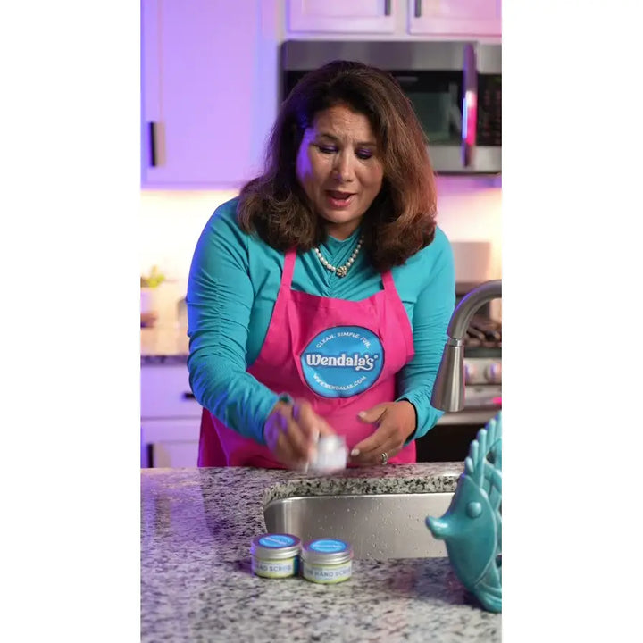 Pink apron with blue circular wendal logo showing organic coconut butter pure cane sugar hand scrub branding