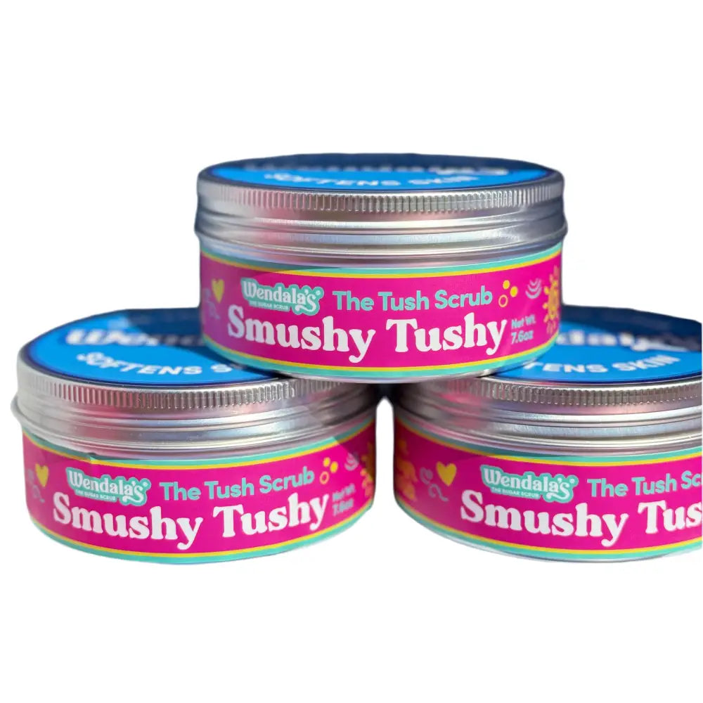 Pink and blue labeled metal jars of wendalas smushytushy body scrub with passion fruit sugar shea butter and organic coconut oil
