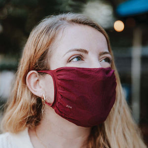 30X Mask, Sangria ear loop mask, worn by a young woman outside